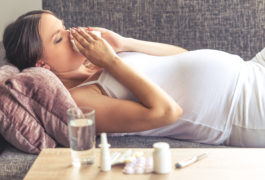 pregnant woman blowing nose and sick on couch