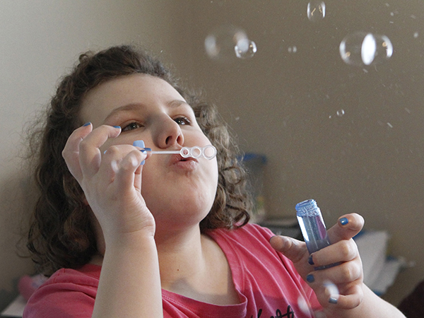 Clear interests: Alex Garish enjoys blowing bubbles in her family's living room when she gets home from school. Photos by Marie-France Coallier