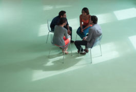 Birdseye view of four adults sitting in a circle talking