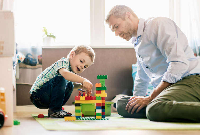 child and father playing with blocks at home