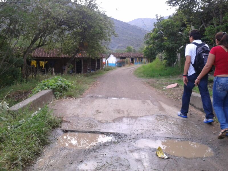 two people walking down dirt road in a town in colubmia